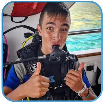 A diver giving a thumbs up while biting on a regulator.