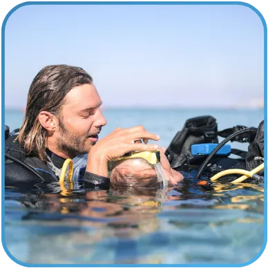 A diver assisting another diver at the surface of the water.