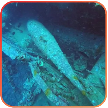 A shipwreck underwater with various parts of the sunken ship visible, surrounded by the deep blue of the ocean.