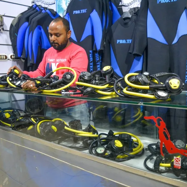 A person arranging various scuba diving regulators on a counter.