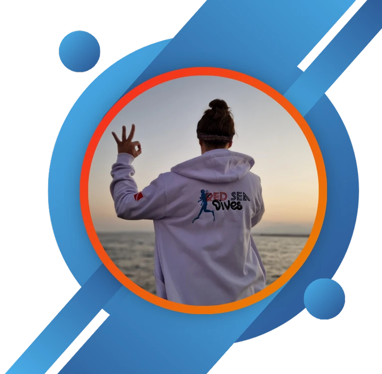 Person in a hoodie with 'Red Sea Dives' logo making a peace sign at sunset, symbolizing a relaxed diving lifestyle.